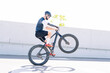 © Jose Luis CARRASCOSA/Westend61 - Male amputee athlete performing stunt with bicycle on road against clear sky