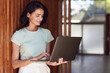© Maya Claussen/Westend61 - Smiling businesswoman using laptop while standing by wooden wall in office