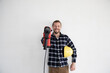 © MiJo/Westend61 - Smiling male worker holding work tool and helmet while standing against wall in house