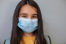Girl With Protective Face Mask Standing Against Gray Wall