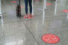 Legs Of Woman Standing On Markings For Social Distancing At Airport