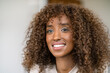 © dirk moll fotografie/Westend61 - Close-up of smiling businesswoman with curly hair contemplating in office