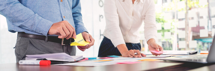 Wall Mural - Creative group of business people brainstorming use sticky notes picking to share idea on table decision Choosing Concept for developing plan in business conference room.