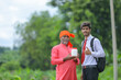© PRASANNAPIX - indian farmer showing agro product bottle with agronomist