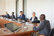 © AnnaStills - Group of business people sitting at the table and listening to speaker during business conference at board room