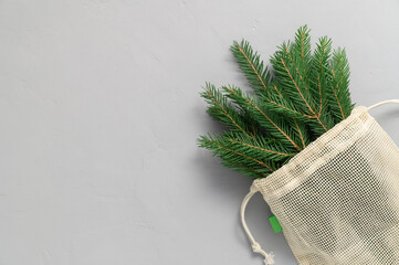 Bouquet of fir branches in fabric eco bag on gray background. Minimal Christmas zero waste concept. Flat lay, Top View, copy space.