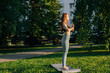 © dikushin - Portrait of attractive redhead young woman with closed eyes practicing yoga and meditation performing namaste pose. Calm female making Namaste gesture outside in city park in evening at sunset.