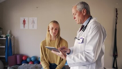 Senior male doctor holding digital tablet showing test results to patient at rehabilitation center