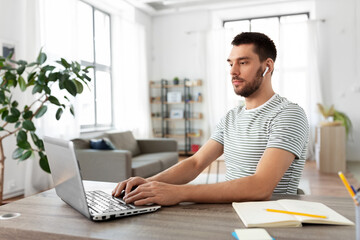 Canvas Print - technology, remote job and business concept - man with laptop computer and earphones working at home office