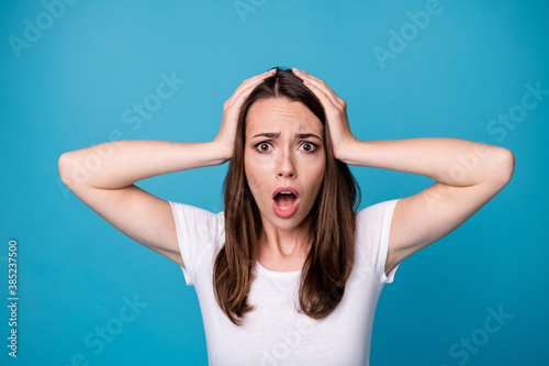 OH NO. Closeup photo of attractive shocked lady open mouth bad mood speechless listen awful terrible horrible news arms on head wear casual white t-shirt isolated blue color background