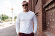 © opolja - Portrait of a Grey-haired Mature handsome man in jeans and white t-shirt leaning to the old wall.