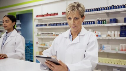 Wall Mural - Caucasian female pharmacist scrolling through scripts on digital tablet smiling wearing coat in clean pharmacy 