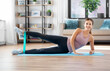 © Syda Productions - sport, fitness and people concept - happy woman exercising with resistance band lying on mat at home