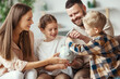 © JenkoAtaman - financial planning   family mother father and children with piggy Bank at home