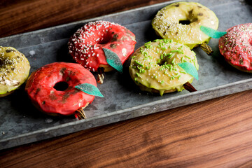 Doughnuts or donuts. Classic American favorite, apple cider donuts iced with maple syrup flavored butter cream frosting and topped with gold leaf sprinkles and decorations.