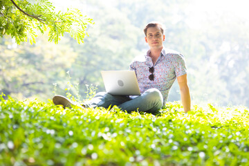 smiling young caucasian man working and learning with laptop outdoors. Video call with girlfriend.