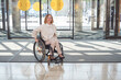 adult woman in wheelchair enters the mall through glass doors. The concept of accessible environment.