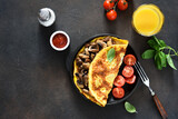 Fototapeta  - Omelet with mushrooms and tomatoes for breakfast with orange sticks on a concrete background.
