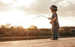 Little boy with fishing rod on river bank