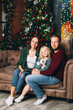 © irina_timokhina - Cute family mom, dad and daughter pose at the Christmas tree