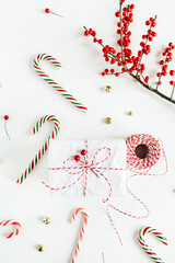 Wall Mural - Christmas gift box with festive candies, branch with red berries, reel of christmas rope on white table. Christmas, new year composition. Flat lay, top view.