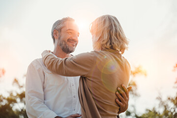 Wall Mural - Romantic and elderly healthy lifestyle concept.Senior active caucasian couple holding hands looks happy in the park in the afternoon autumn sunlight,happy anniversary,happily retired with copy space.