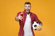 Excited young man football fan in red shirt cheer up support favorite team with soccer ball bottle of beer bowl of chips isolated on yellow background studio portrait. People sport leisure concept.