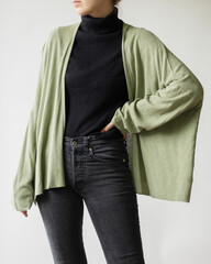 Wall Mural - Young woman wearing simple outfit with black turtleneck, green jumper and black jeans isolated on white background.