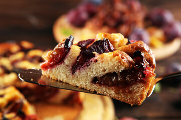 Wall Mural - Rustic plum cake on wooden background with plums around.