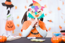 Smiling Young Girl Put Her Painted Witch Mask On Face For Halloween Party