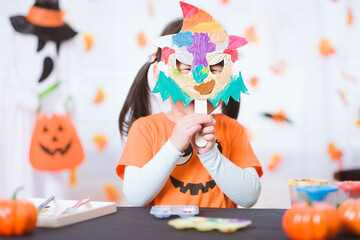 smiling young girl put her painted witch mask on face for Halloween party