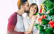 © My Ocean studio - Cute excited happy couple in love are hugging each other and decorating christmas tree while winter holidays at home