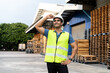 © twinsterphoto - Portrait of young Indian worker working in logistic industry outdoor in front of factory warehouse. Smiling happy man with industrial hard hat looking far away hands on hip at depot