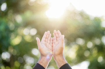 Praying male hands for hope stretch into the sky on nature background with sun light. Religion and belief concept.