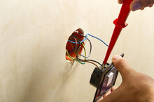 Electrician Installing Light Switch On Painted Wall With Screwdriver. Man Installing Light Switch After Home Renovation.