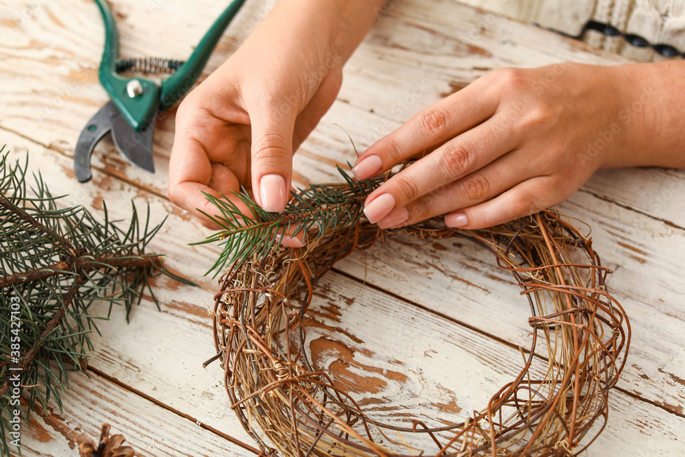 Woman making beautiful Christmas wreath on table