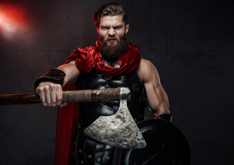 warlike and aggressive roman fighter with beard and red cloak in dark armor posing with outstretched