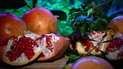 Wall Mural - Pomegranate fruit. Fresh and ripe red pomegranate and pomegranate seeds, green garden in the background. Organic Bio fruits close-up. 4K UHD video.