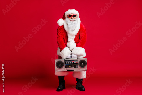 Full body size photo of retired old man grey beard hold boombox starting dance hip-hop battle wear santa costume sunglass headwear leather black boots isolated red color background