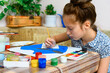 © soleg - a girl drawing blue gouache cardboard, artistic creation at home, makes creative artwork