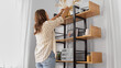 © Syda Productions - home improvement, decoration and people concept - woman placing dried flowers or herbs in vase to shelf