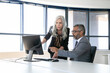 © Mangostar - Serious colleagues watching and discussing content on computer monitor, pointing at display and talking while sitting in meeting room with panoramic window. Business communication concept