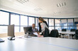 © Mangostar - Company managers gathering in meeting room, watching project presentation on computer monitor together, holding paper report. Business communication or teamwork concept