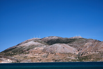 Canvas Print - rocky coast and windmills on a hill on the island of Kefalonia