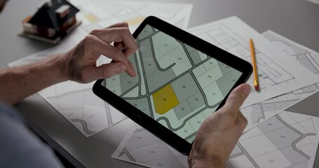 Wall Mural - man searching building plot to buy on cadastral plan for house construction on digital tablet