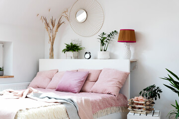 Wall Mural - Cozy bedroom with bed, pink pillows and blanket in scandinavian design. Interior of bedroom with white wall, mirror and plants. Comfortable  room in hotel.