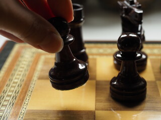 fingers taking a piece of a wooden chessboard