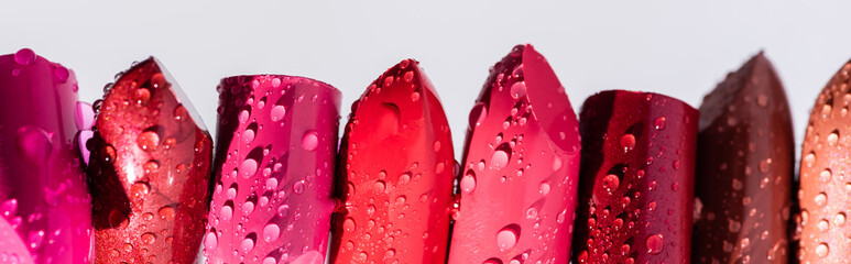 Wall Mural - Close up view of wet lipsticks in row isolated on white, panoramic shot