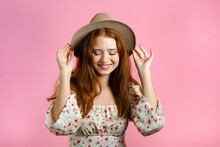 Young Smiling Woman With Red Hairstyle And Hat. Portrait Of Cute Beautiful Girl On Pink Studio Wall Background.