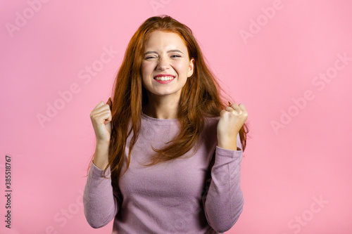 Fotomural Woman with red hair very glad and happy, she shows yes gesture of victory, she achieved result, goals